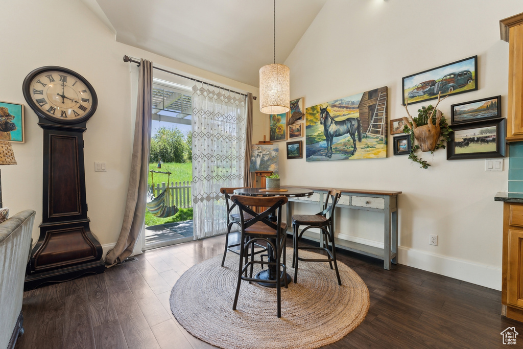 Dining area featuring dark wood-type flooring, baseboards, and vaulted ceiling