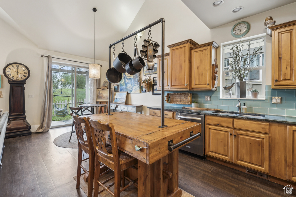 Kitchen featuring brown cabinetry, backsplash, dark wood finished floors, dishwasher, and a sink