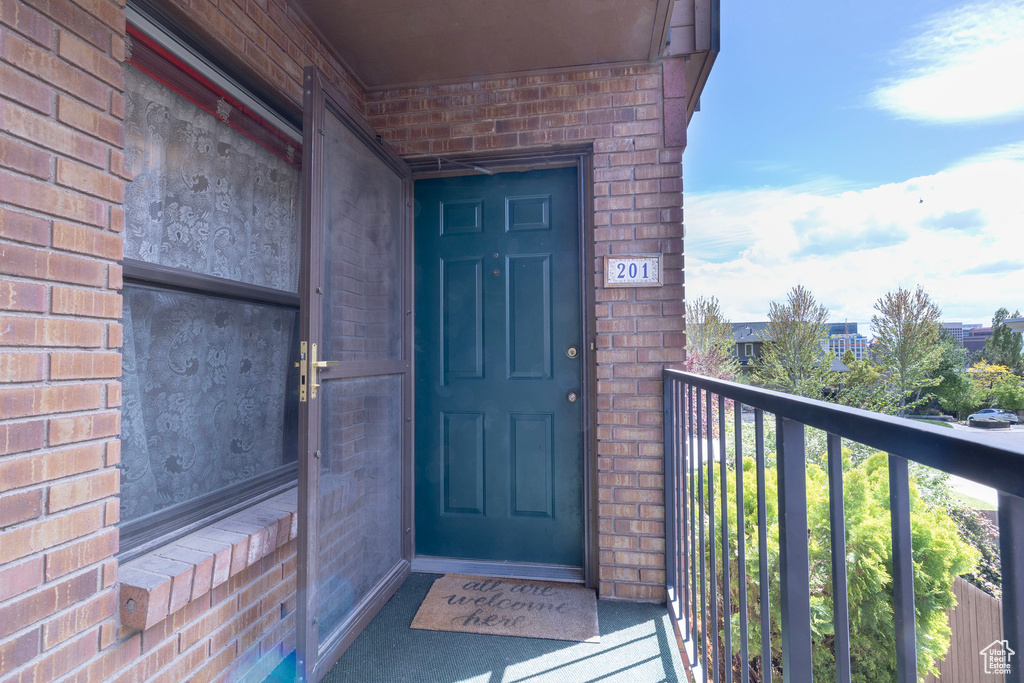 Doorway to property with a balcony and brick siding