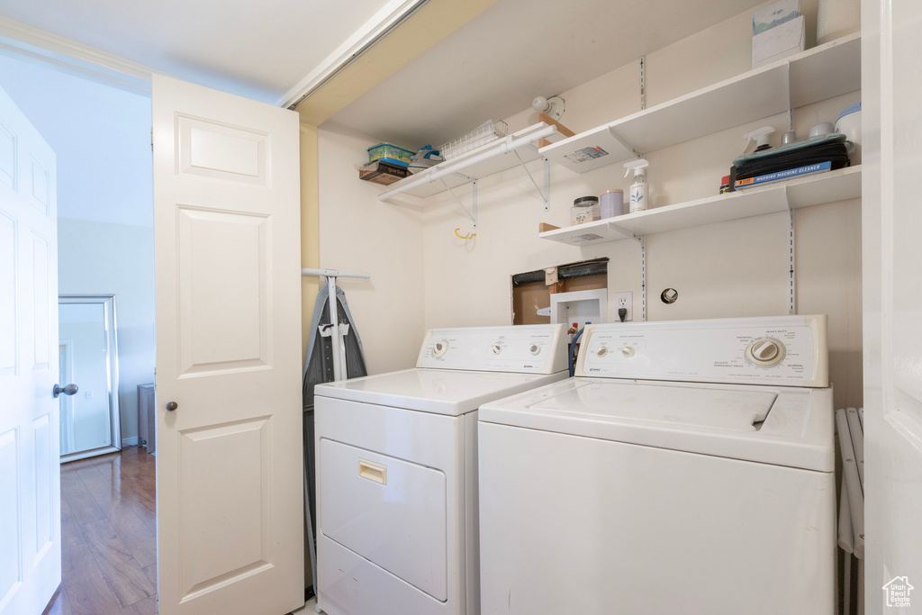 Clothes washing area featuring wood finished floors, independent washer and dryer, and laundry area