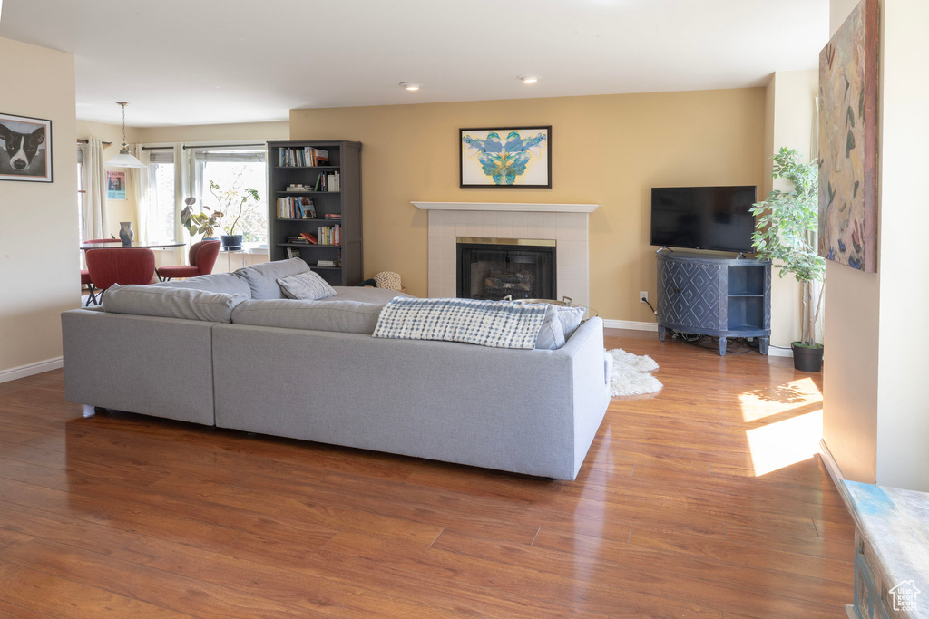 Living room with baseboards, light wood-type flooring, a fireplace, and recessed lighting