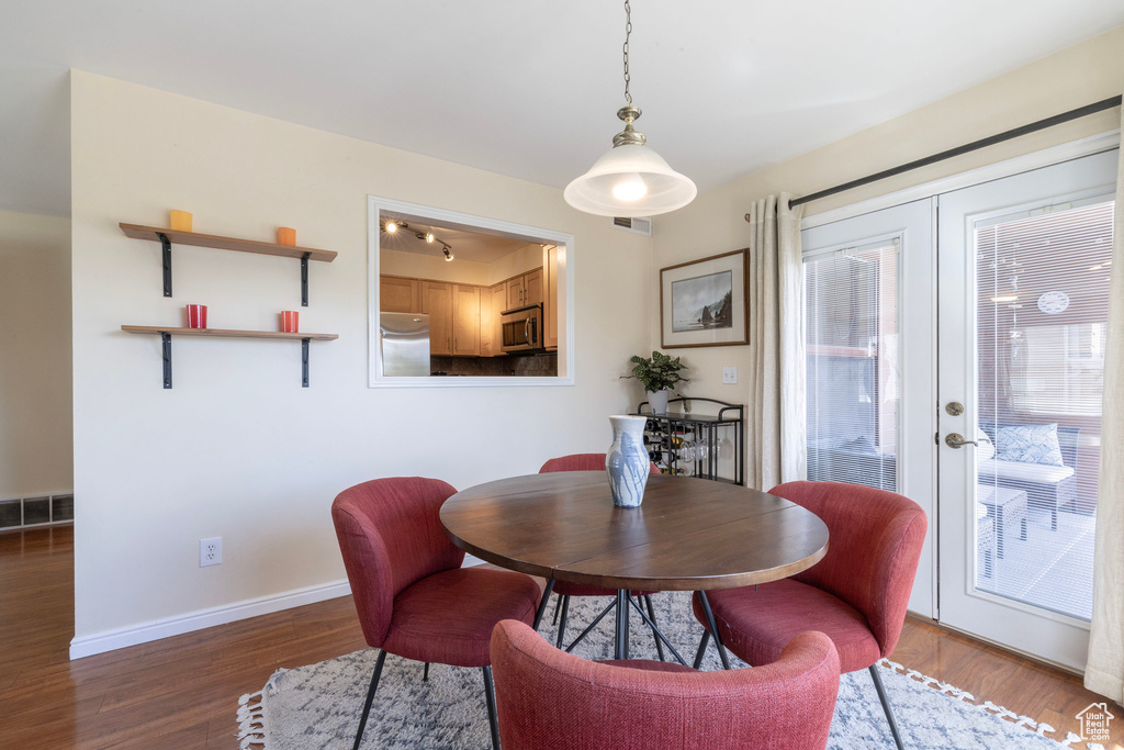 Dining space with wood finished floors, french doors, visible vents, and baseboards