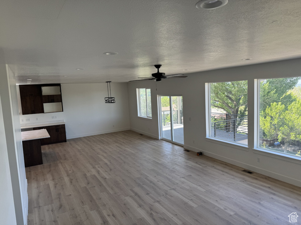 Unfurnished living room featuring baseboards, a ceiling fan, light wood-style flooring, and visible vents