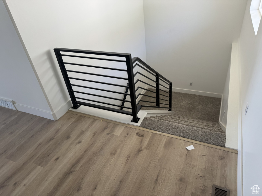 Staircase with baseboards, wood finished floors, and visible vents