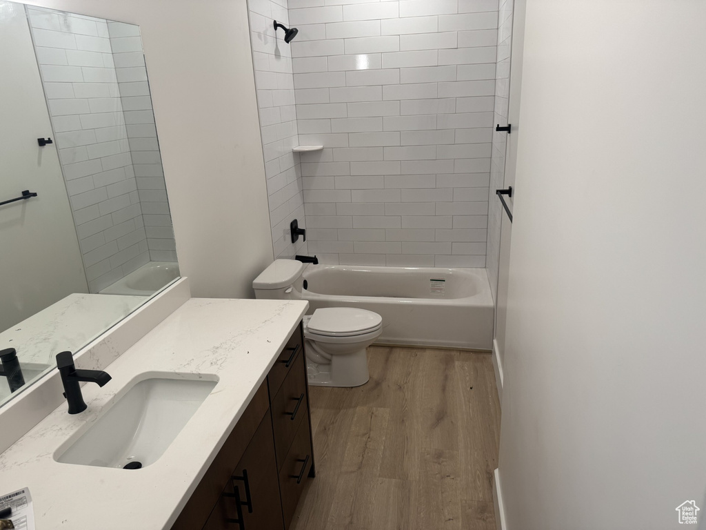 Bathroom with toilet, wood finished floors, shower / bathing tub combination, and vanity