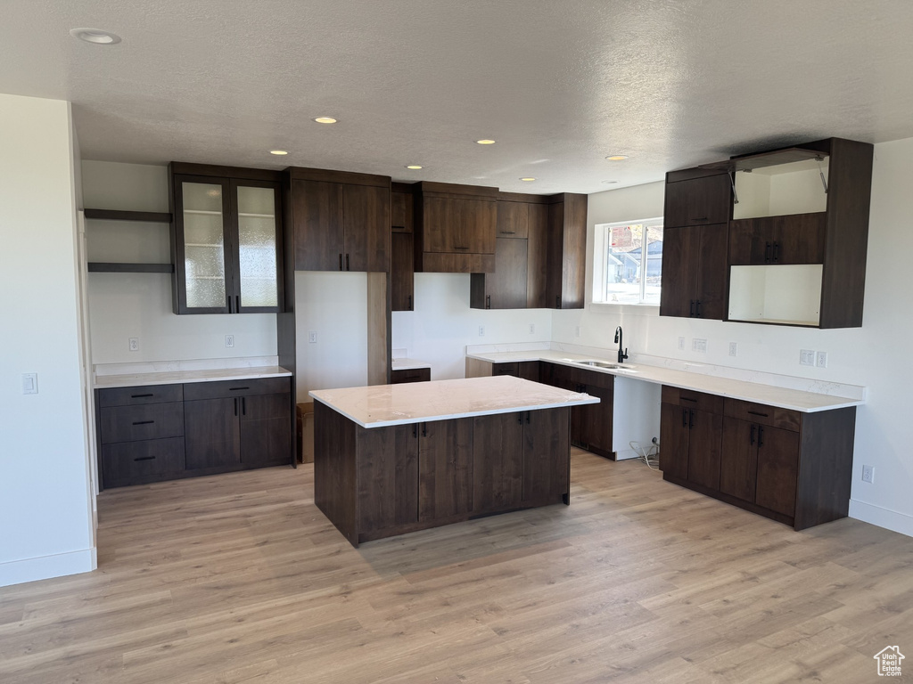 Kitchen with dark brown cabinets, open shelves, a sink, baseboards, and a kitchen island