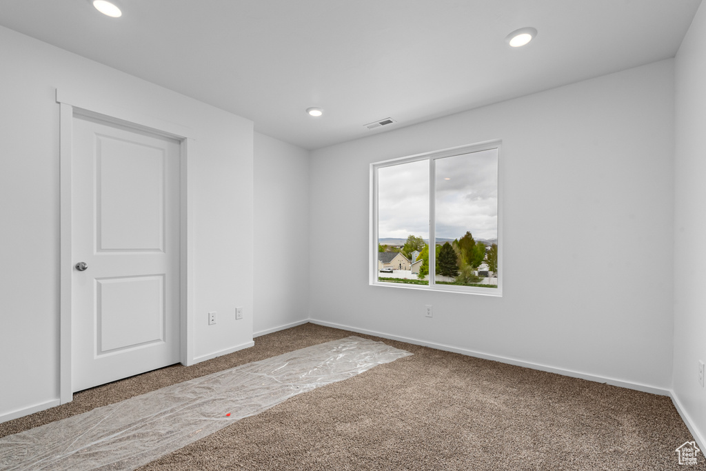 Empty room with carpet floors, recessed lighting, baseboards, and visible vents