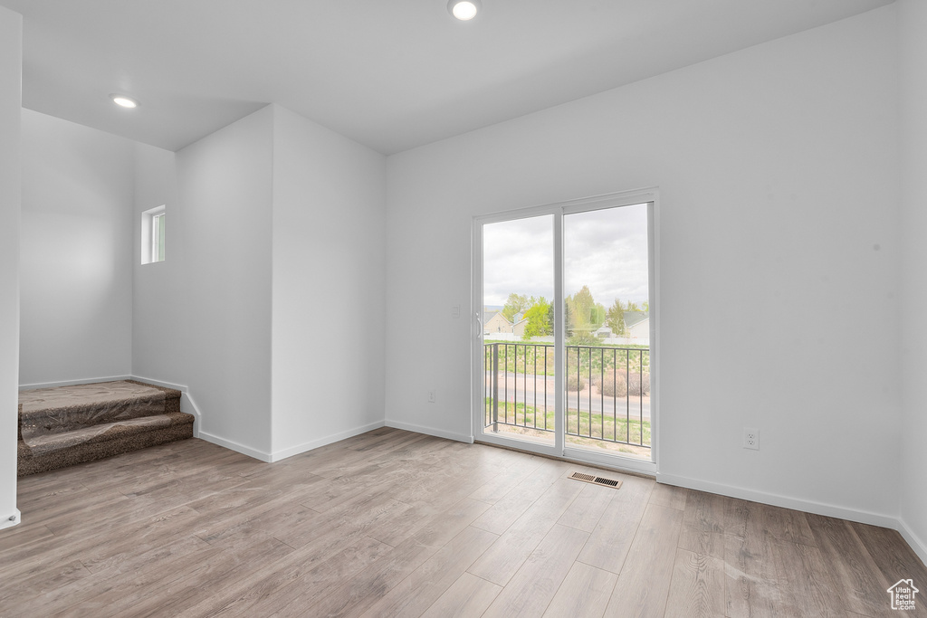 Unfurnished room featuring visible vents, light wood finished floors, stairs, and a wealth of natural light