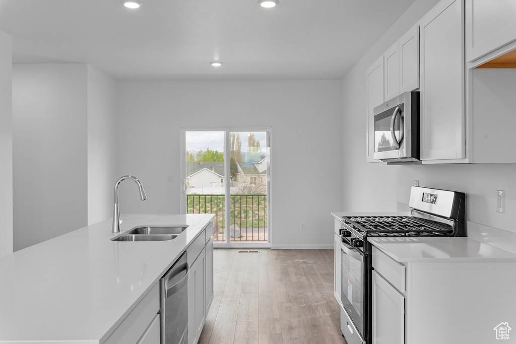 Kitchen featuring recessed lighting, appliances with stainless steel finishes, a sink, and light wood finished floors