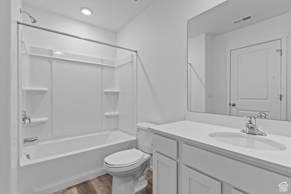 Bathroom with visible vents, vanity, tub / shower combination, wood finished floors, and toilet