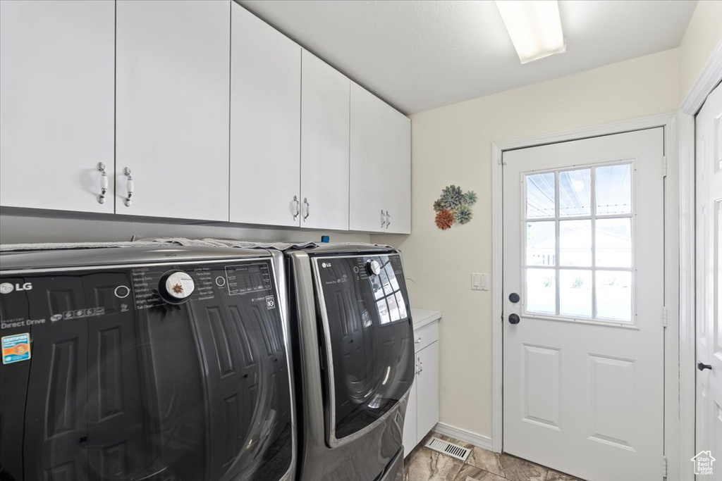 Washroom featuring cabinet space, baseboards, visible vents, and washing machine and dryer