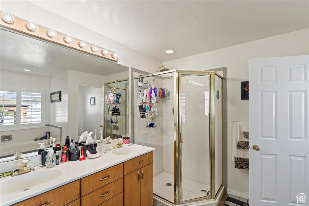Full bathroom with double vanity, a shower stall, and a sink