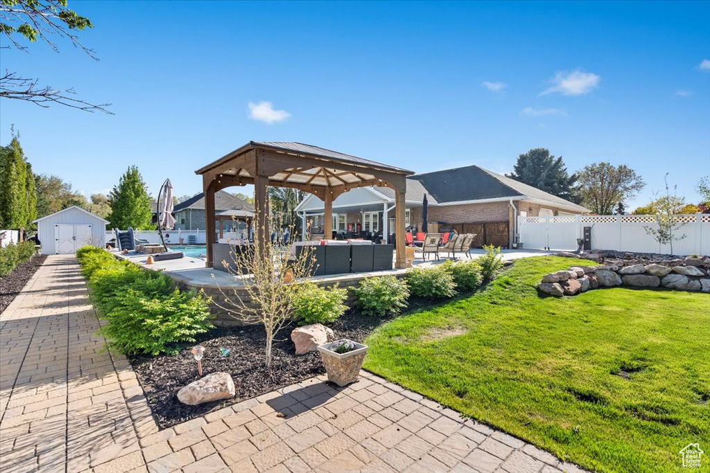 View of patio with a gazebo, a fenced in pool, an outdoor hangout area, a fenced backyard, and a shed