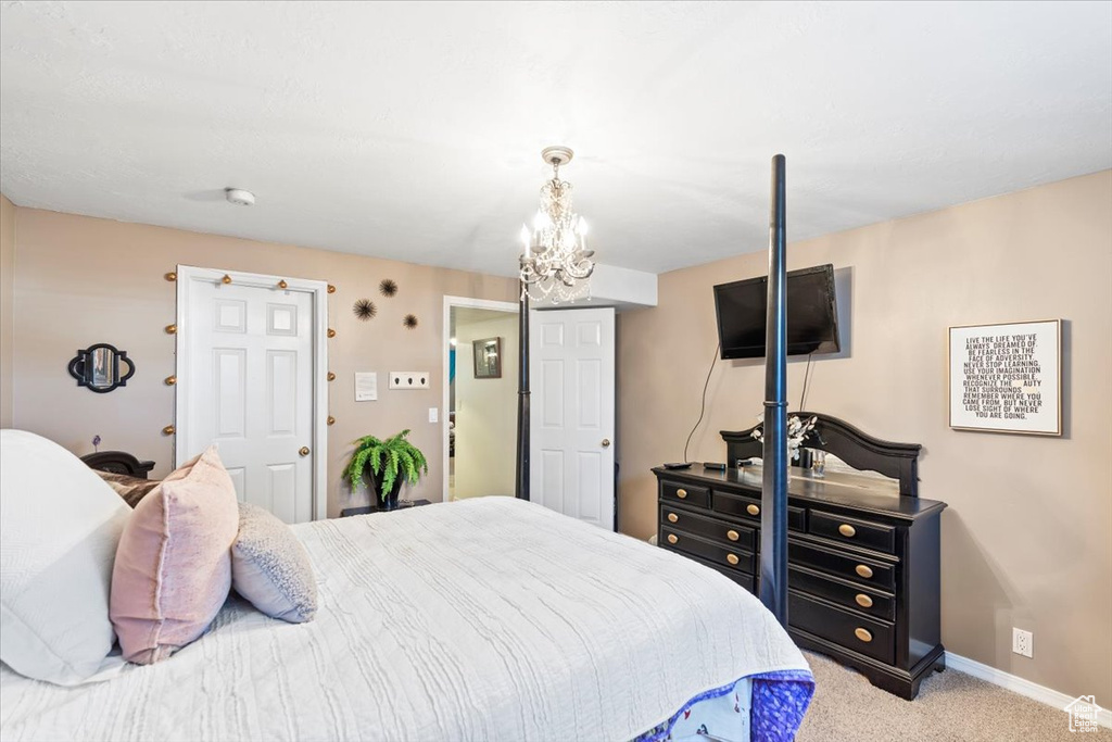 Carpeted bedroom with baseboards and a notable chandelier