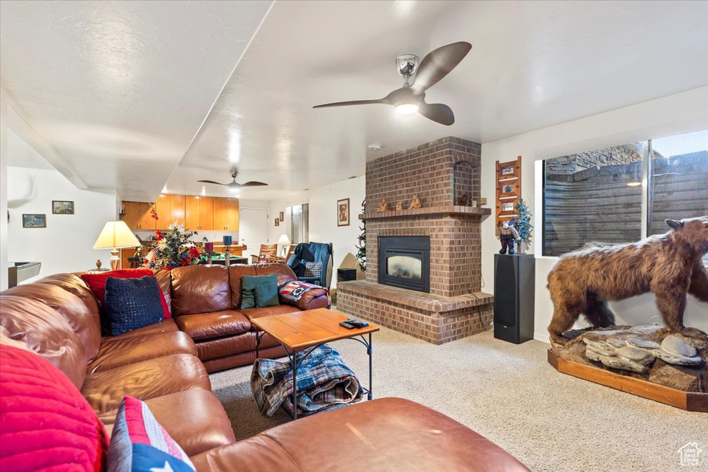Carpeted living area featuring a brick fireplace and ceiling fan