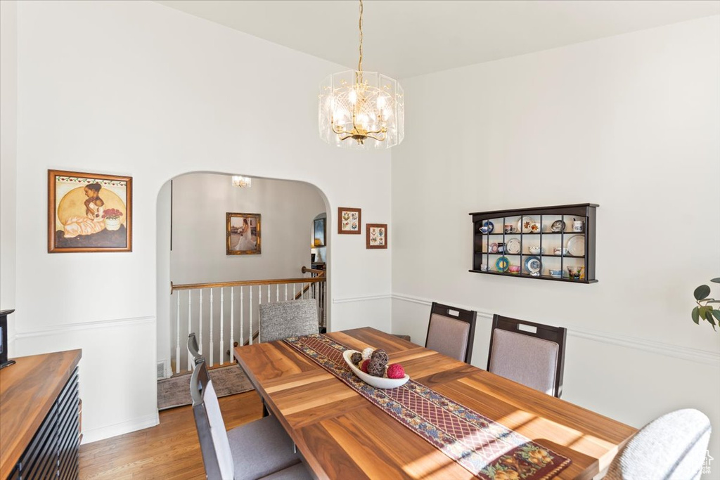 Dining room with arched walkways, an inviting chandelier, and wood finished floors