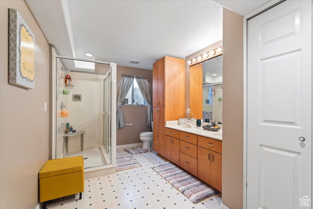 Full bath with vanity, toilet, tile patterned floors, visible vents, and a stall shower
