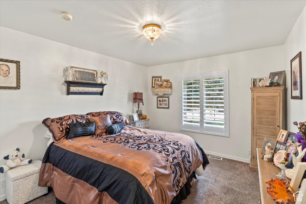Carpeted bedroom featuring baseboards and visible vents