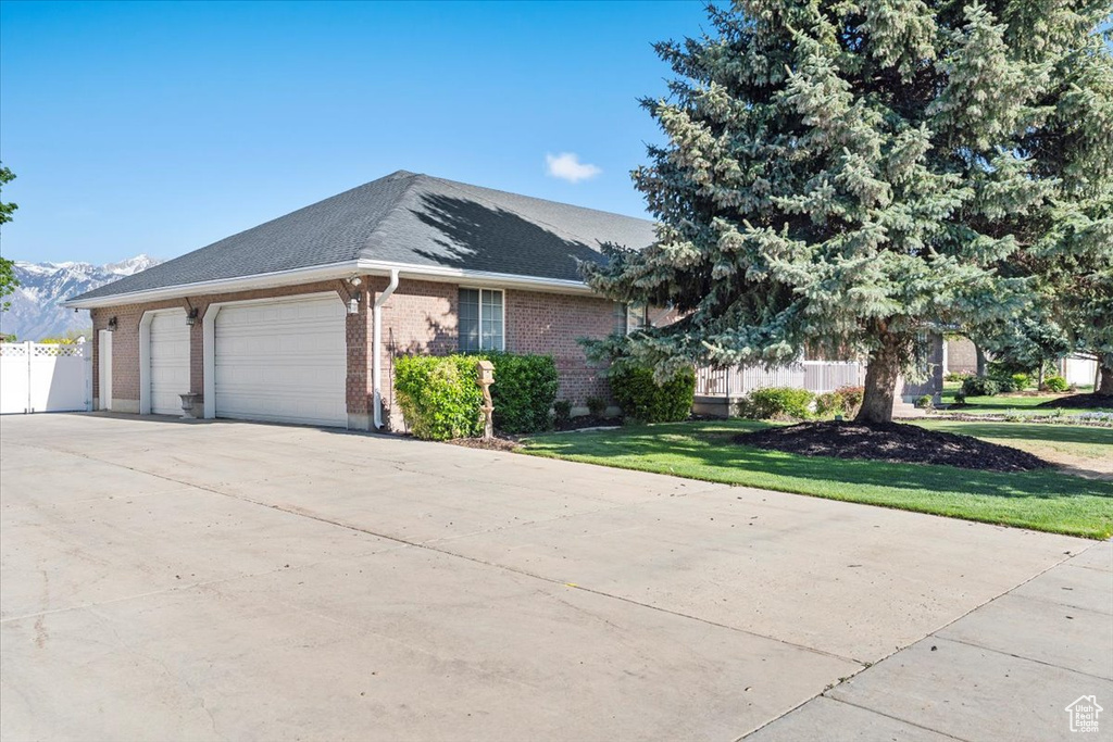 Ranch-style home featuring fence, an attached garage, a front lawn, brick siding, and driveway