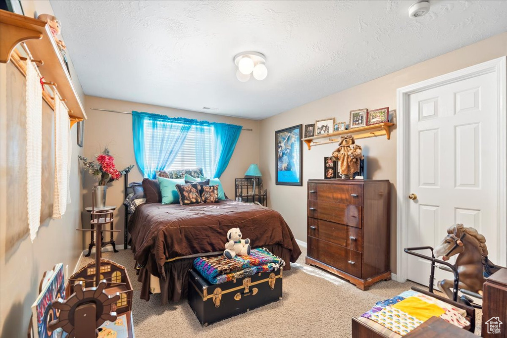 Carpeted bedroom featuring baseboards and a textured ceiling