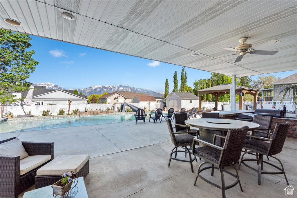 View of patio / terrace with outdoor dining space, a gazebo, a storage shed, a fenced backyard, and a mountain view