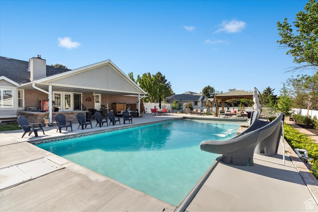 View of pool with a patio, a gazebo, a water slide, and a fenced in pool