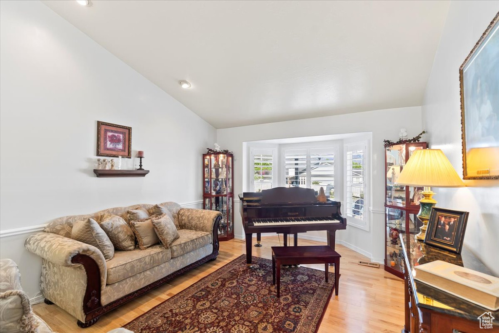 Living room featuring recessed lighting, baseboards, light wood finished floors, and lofted ceiling