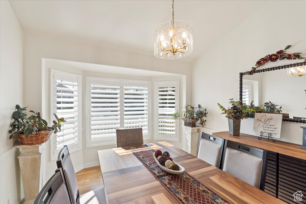 Dining room featuring baseboards, wood finished floors, a notable chandelier, and vaulted ceiling