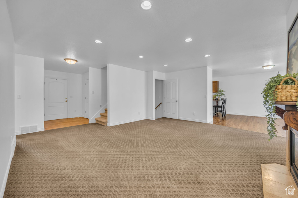 Living room with light colored carpet, recessed lighting, stairs, and visible vents