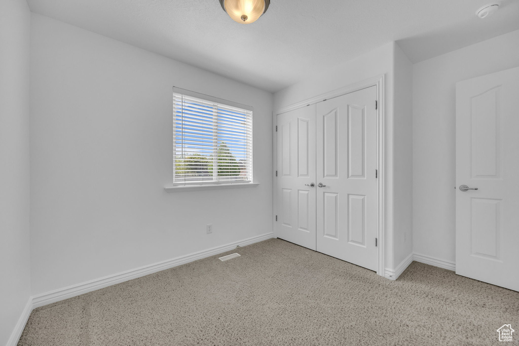 Unfurnished bedroom featuring baseboards, carpet flooring, and a closet