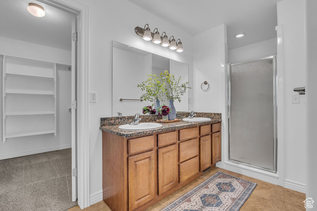 Bathroom featuring double vanity, a sink, and a stall shower