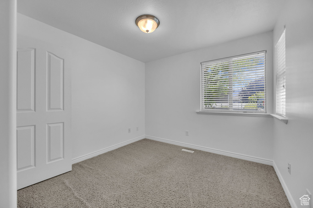 Carpeted spare room with baseboards and visible vents