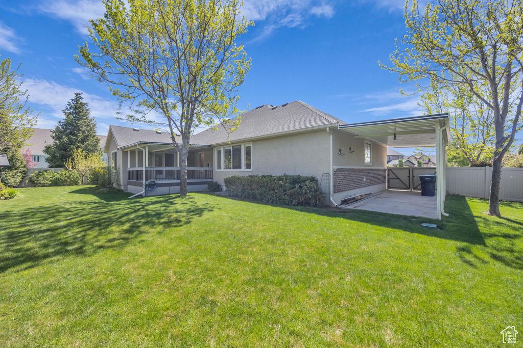 Back of property with a lawn, brick siding, fence, and a sunroom