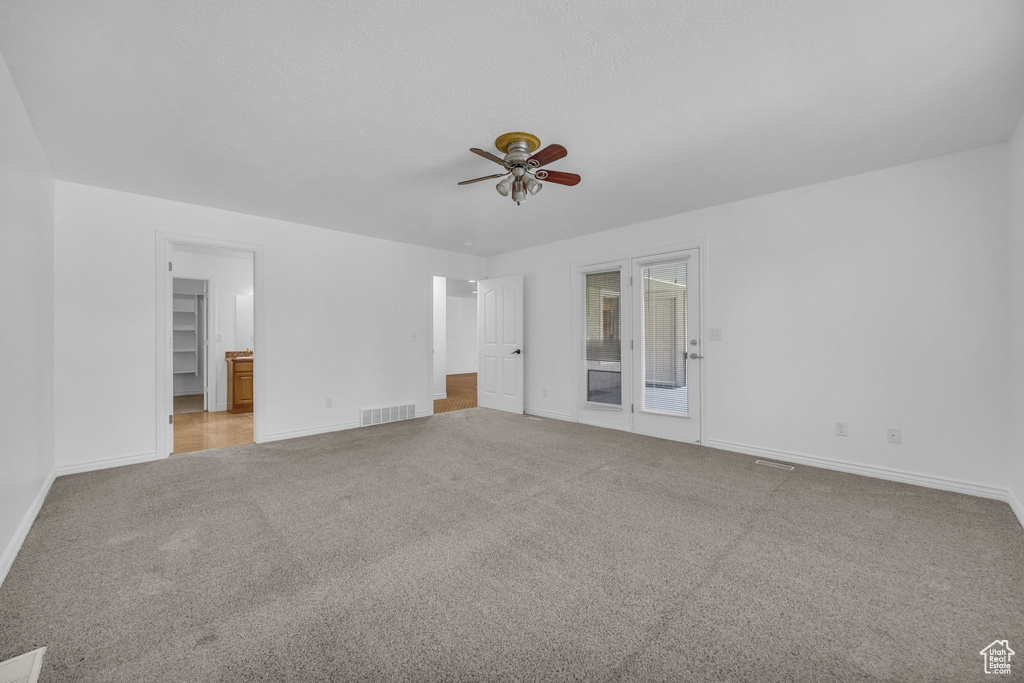 Interior space featuring baseboards, visible vents, a ceiling fan, and light colored carpet
