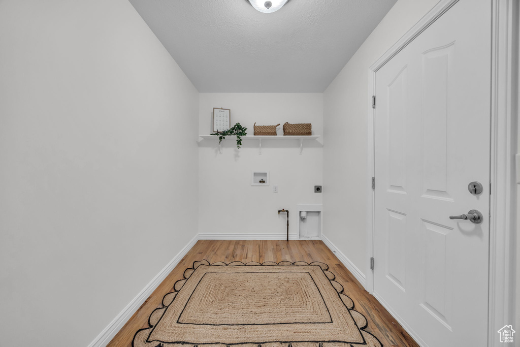 Clothes washing area featuring hookup for an electric dryer, laundry area, washer hookup, and wood finished floors