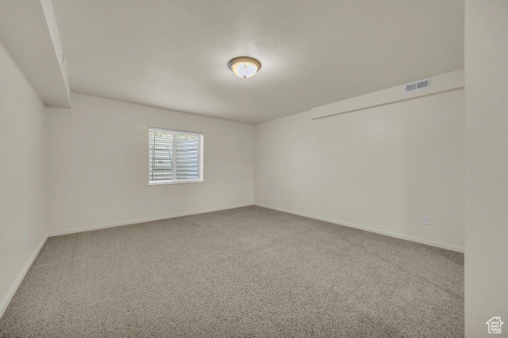 Carpeted spare room featuring visible vents and baseboards