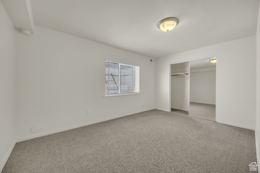 Unfurnished bedroom featuring carpet floors, baseboards, and a closet