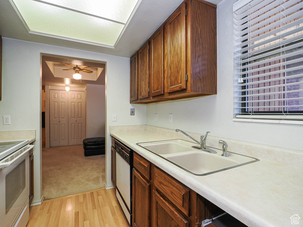 Kitchen featuring ceiling fan, a sink, light wood-style floors, white appliances, and light countertops