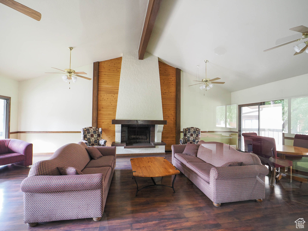 Living room featuring ceiling fan, beam ceiling, high vaulted ceiling, a large fireplace, and wood finished floors