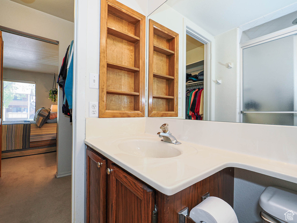 Full bath with vanity, a shower with door, and a spacious closet
