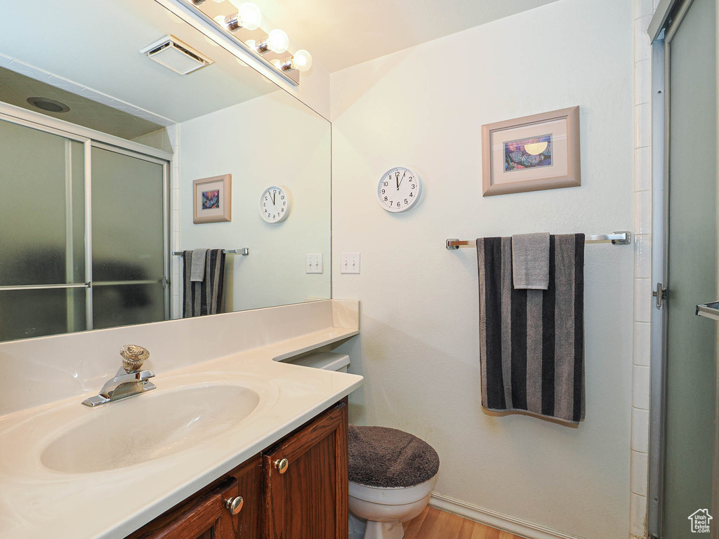 Bathroom with visible vents, a stall shower, wood finished floors, vanity, and toilet