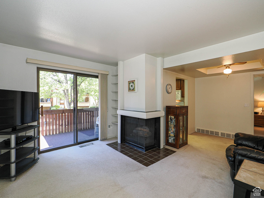 Carpeted living room with built in features, a multi sided fireplace, and visible vents
