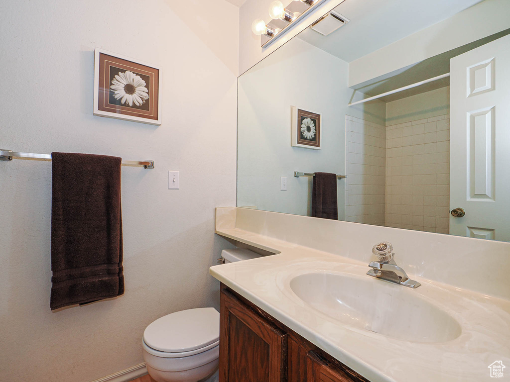 Full bath with vanity, toilet, a shower, and visible vents