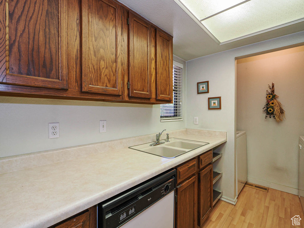 Kitchen featuring visible vents, white dishwasher, light countertops, a sink, and light wood-style flooring