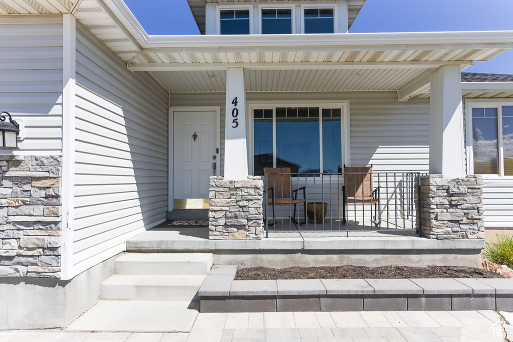 View of exterior entry featuring a porch and stone siding