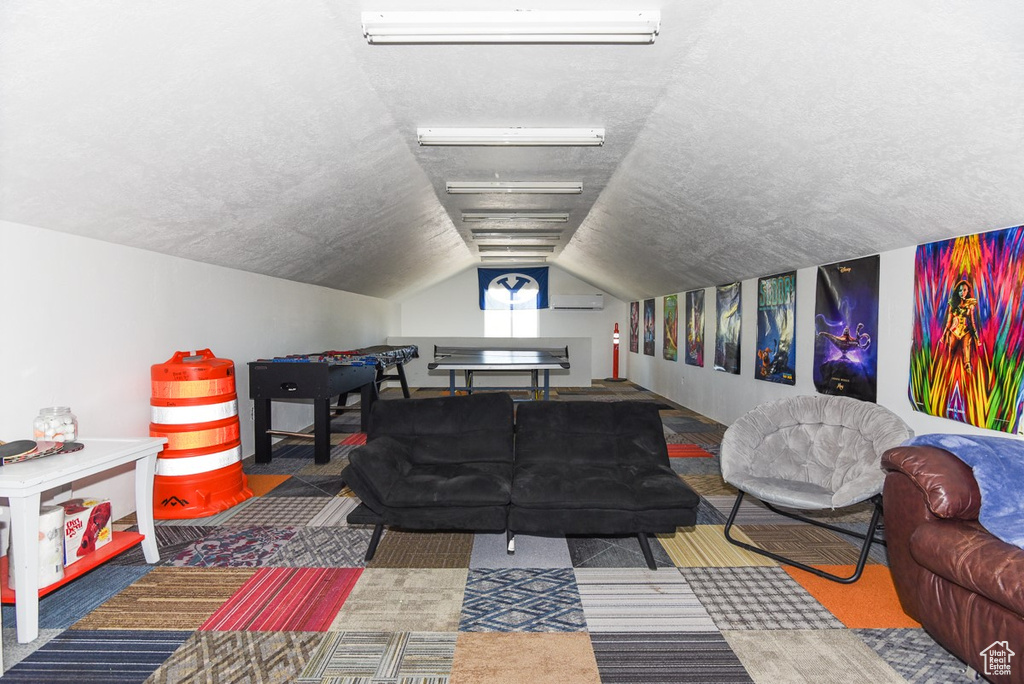 Game room featuring carpet flooring, a textured ceiling, a wall mounted AC, and lofted ceiling