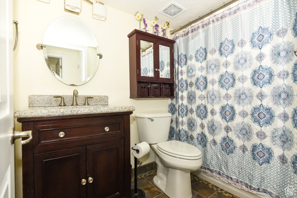 Full bath featuring vanity, visible vents, curtained shower, toilet, and tile patterned floors