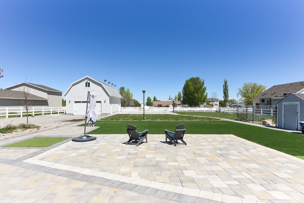 View of patio with a detached garage, fence, and an outdoor structure