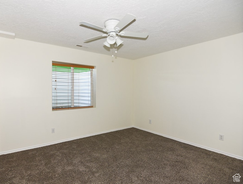 Unfurnished room featuring visible vents, a textured ceiling, ceiling fan, and dark carpet