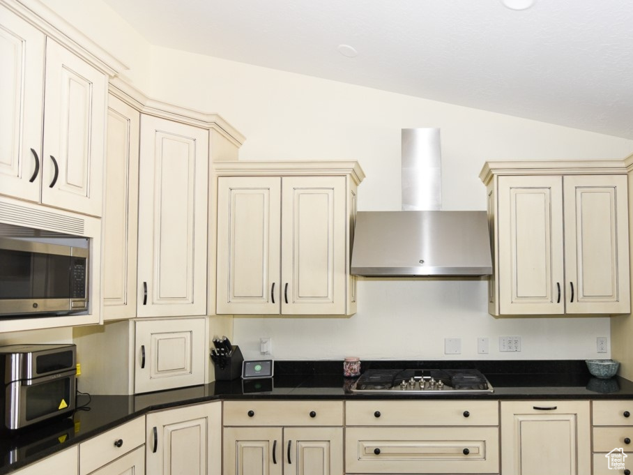 Kitchen with a sink, cream cabinets, stainless steel appliances, and wall chimney exhaust hood